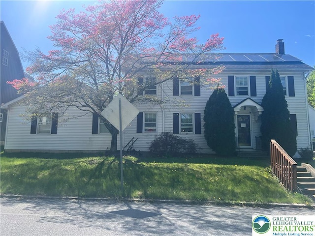 8204 Brown St, Washington Twp, PA 18079 - colonial inspired home featuring roof mounted solar panels, a front yard, and a chimney