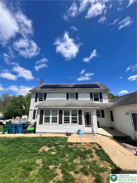 8204 Brown St, Washington Twp, PA 18079 - back of house featuring roof mounted solar panels, a patio, a chimney, and a lawn