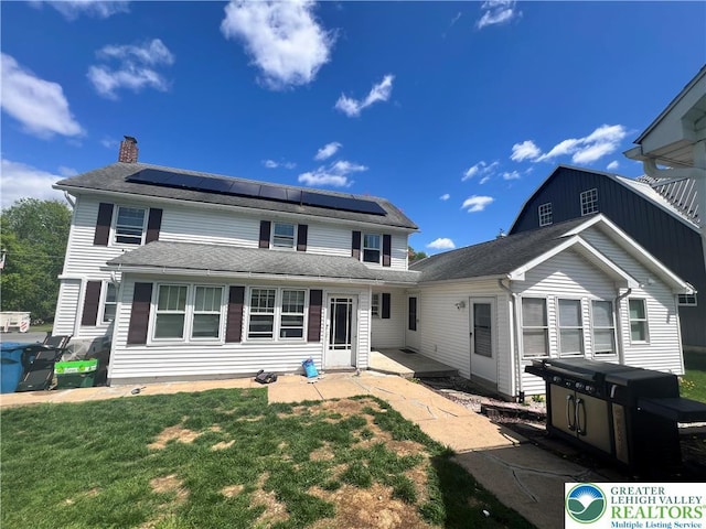 8204 Brown St, Washington Twp, PA 18079 - back of property with roof mounted solar panels, a chimney, a lawn, and a patio area