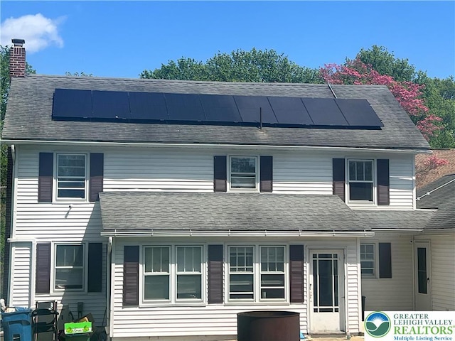 8204 Brown St, Washington Twp, PA 18079 - view of front facade featuring a shingled roof, roof mounted solar panels, and a chimney