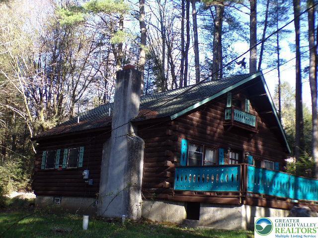 view of side of home with log siding and a chimney
