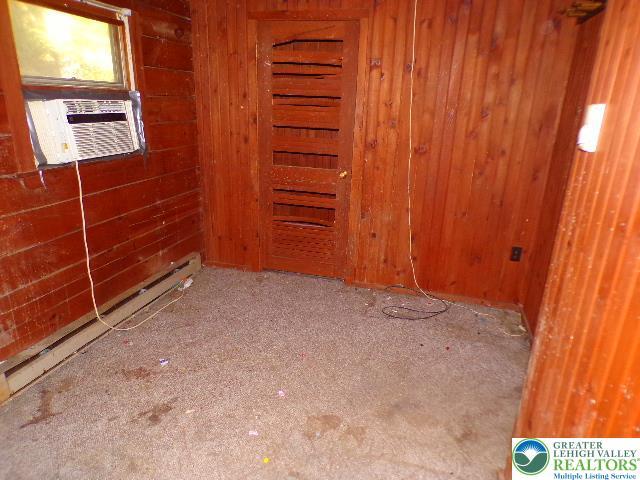 unfurnished room featuring carpet floors, a baseboard radiator, cooling unit, and wood walls