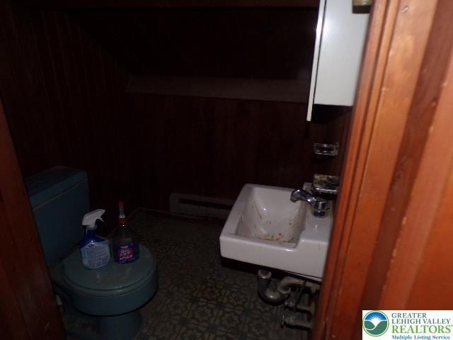 half bathroom with a baseboard radiator, a sink, and toilet