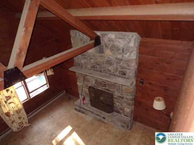 interior space with wooden walls and a stone fireplace