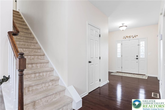 entrance foyer with stairway, baseboards, wood finished floors, and visible vents