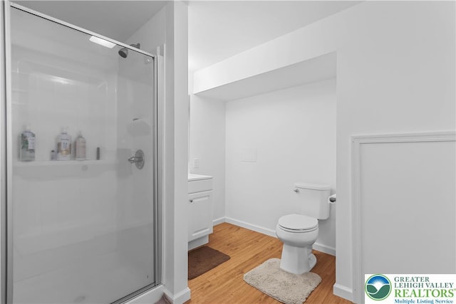 full bathroom with vanity, toilet, baseboards, wood finished floors, and a stall shower