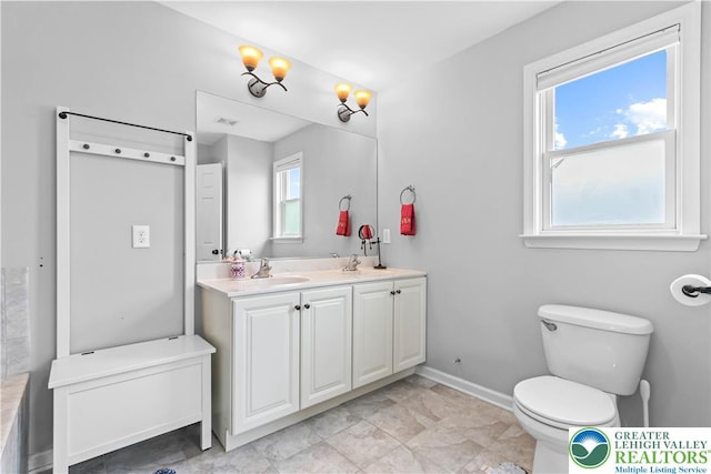 full bath featuring a sink, baseboards, toilet, and double vanity