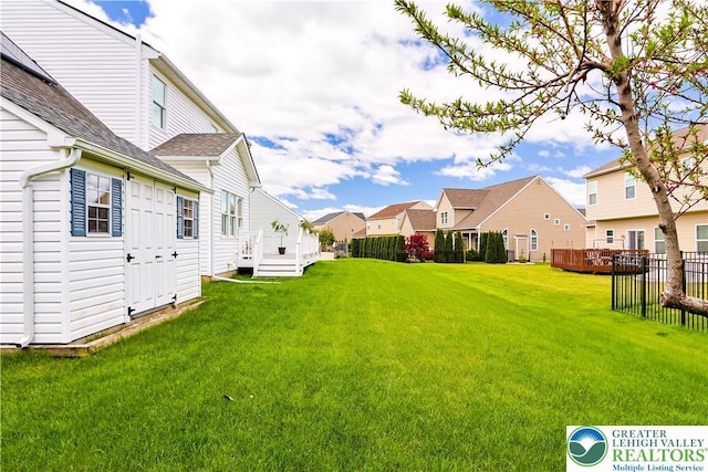 view of yard featuring a residential view, fence, and a wooden deck