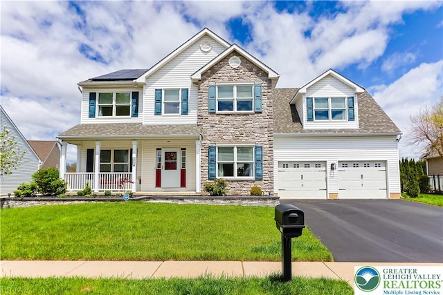 craftsman inspired home with a garage, a front lawn, aphalt driveway, stone siding, and a porch