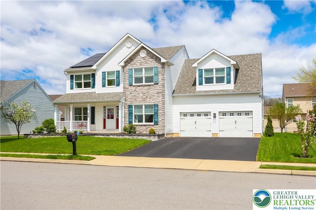 view of front facade featuring an attached garage, a front lawn, stone siding, a porch, and driveway