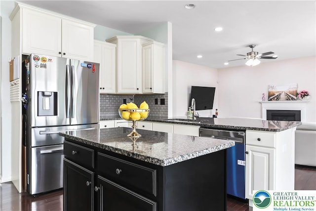 kitchen with a peninsula, open floor plan, ceiling fan, dark cabinets, and appliances with stainless steel finishes