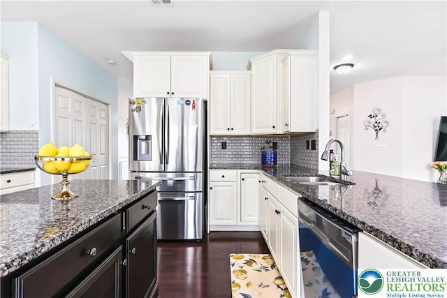 kitchen with stainless steel fridge, a sink, dishwashing machine, and white cabinetry