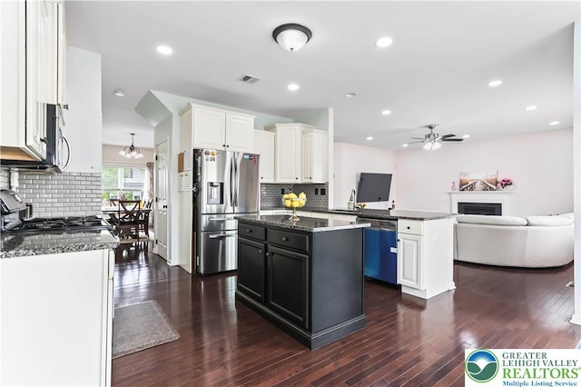 kitchen featuring visible vents, ceiling fan with notable chandelier, a center island, tasteful backsplash, and appliances with stainless steel finishes