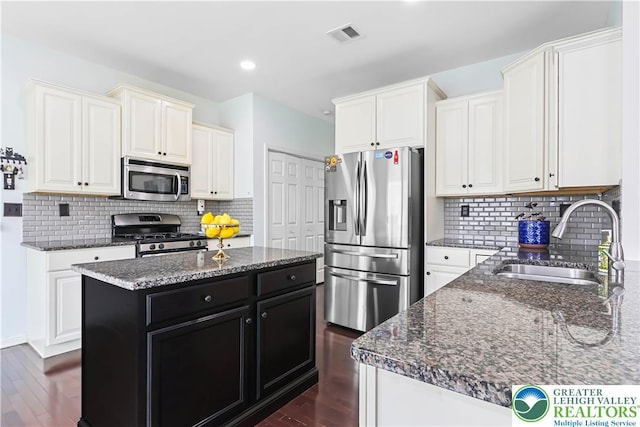 kitchen with a sink, dark stone counters, dark cabinetry, and stainless steel appliances