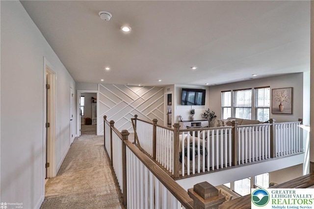 hall featuring light colored carpet, recessed lighting, baseboards, and an upstairs landing