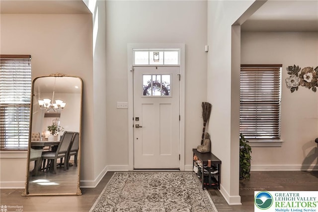 foyer entrance featuring baseboards, an inviting chandelier, and wood finished floors