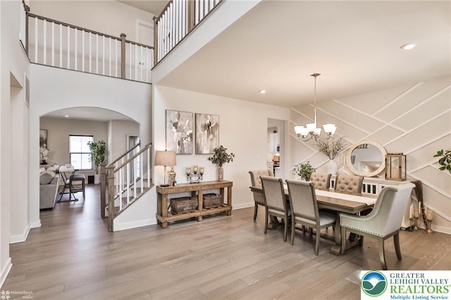 dining space featuring arched walkways, wood finished floors, and stairway