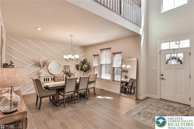 dining space with plenty of natural light, a high ceiling, wood finished floors, and a chandelier