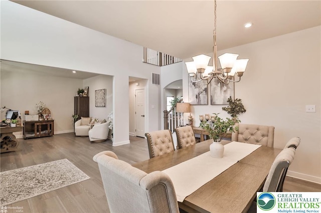 dining area with visible vents, arched walkways, wood finished floors, baseboards, and a notable chandelier