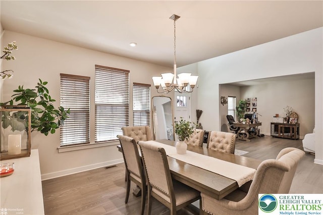 dining space featuring baseboards, wood finished floors, a notable chandelier, and visible vents