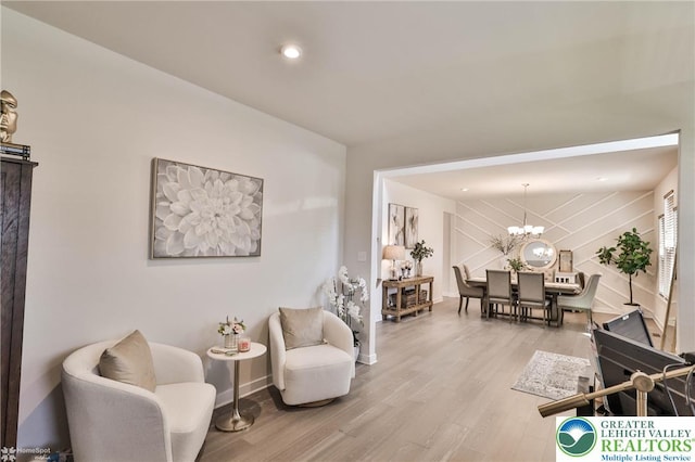 living area with an inviting chandelier, baseboards, and wood finished floors
