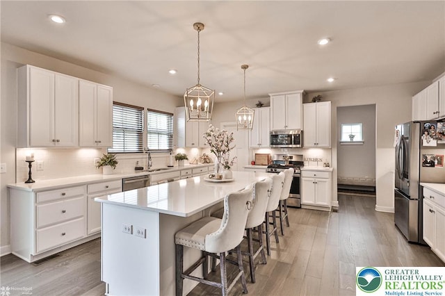 kitchen featuring decorative backsplash, white cabinets, stainless steel appliances, and a kitchen bar