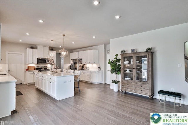kitchen featuring dark wood-style flooring, stainless steel appliances, white cabinetry, and a kitchen breakfast bar