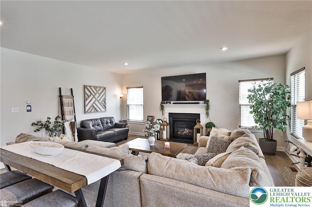 living area featuring recessed lighting, baseboards, a glass covered fireplace, and dark wood-style floors