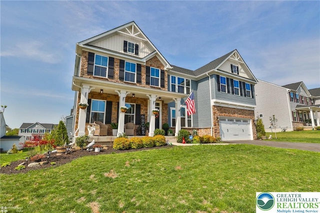 craftsman house with a garage, a front yard, stone siding, a porch, and driveway