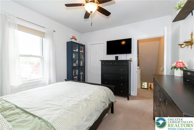 bedroom with a ceiling fan, light carpet, and a closet
