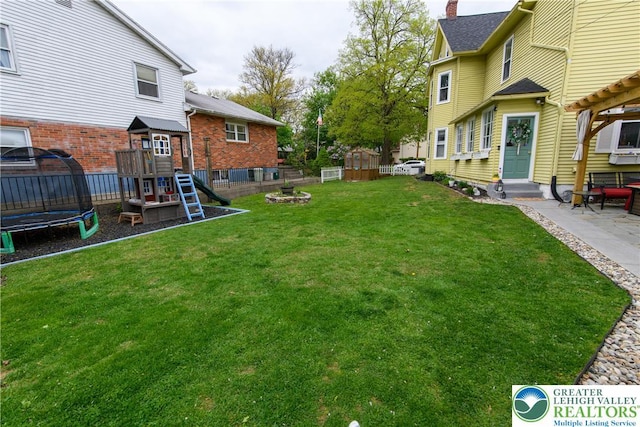 view of yard with entry steps, fence, a trampoline, and a playground