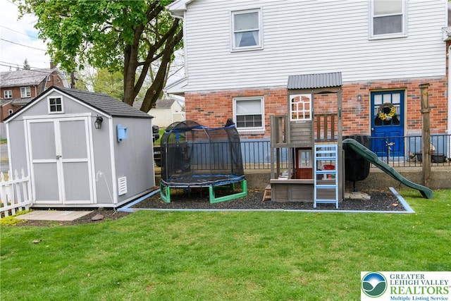 view of play area with fence, a trampoline, a storage shed, an outbuilding, and a yard