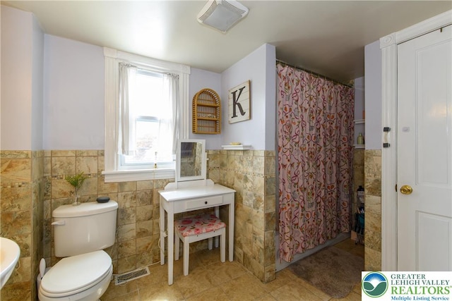 bathroom with tile walls, a wainscoted wall, tile patterned floors, and visible vents
