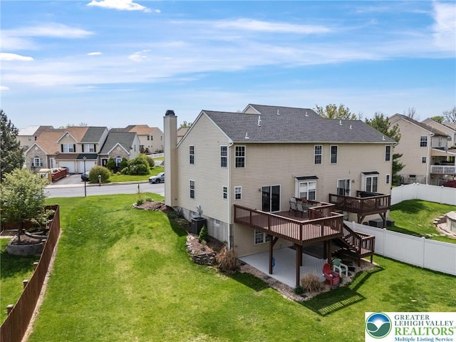back of house with a residential view, a wooden deck, a yard, and central AC