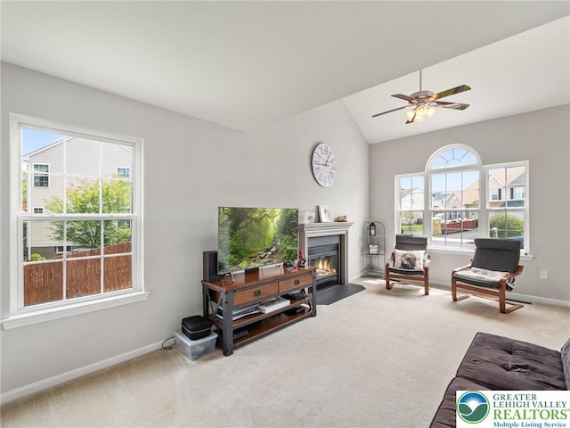 carpeted living area with baseboards, a fireplace with flush hearth, ceiling fan, and lofted ceiling
