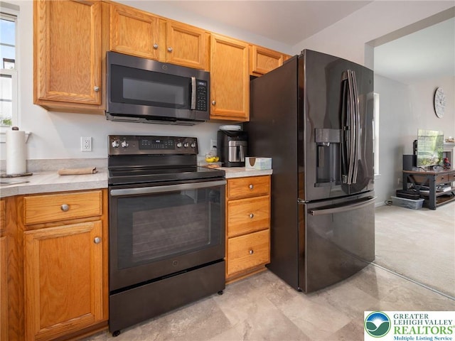 kitchen with light countertops, brown cabinets, and black appliances