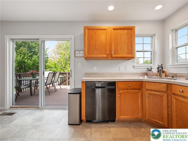 kitchen featuring stainless steel dishwasher, light countertops, brown cabinetry, and recessed lighting