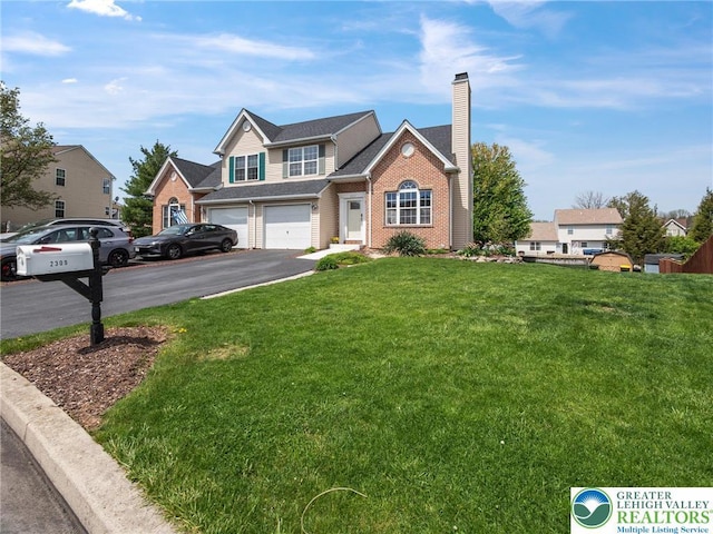 traditional-style house with a front lawn, aphalt driveway, a chimney, brick siding, and an attached garage