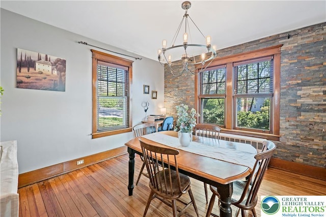 dining space with an inviting chandelier, baseboards, and hardwood / wood-style flooring