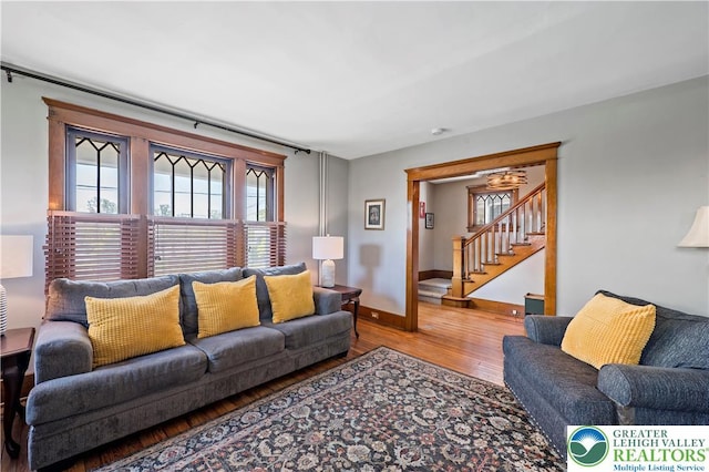living room with stairway, baseboards, wood finished floors, and a wealth of natural light
