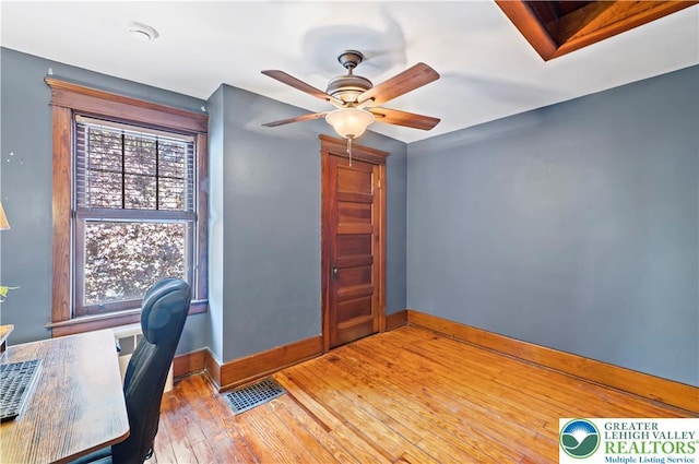 office space with baseboards, ceiling fan, hardwood / wood-style floors, and visible vents