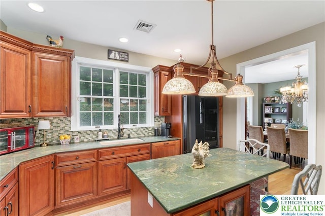 kitchen featuring brown cabinetry, a sink, and black refrigerator