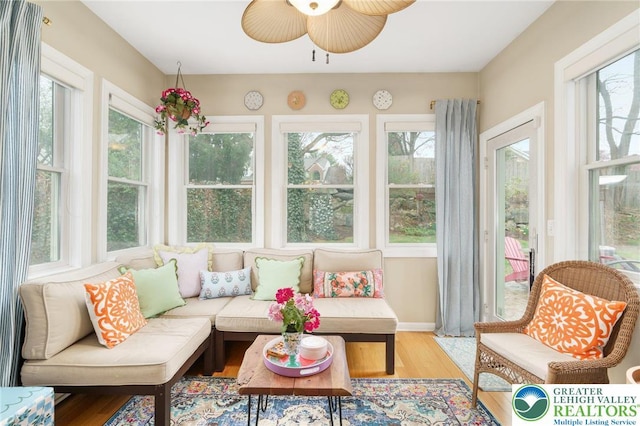 sunroom / solarium with baseboards, plenty of natural light, and wood finished floors
