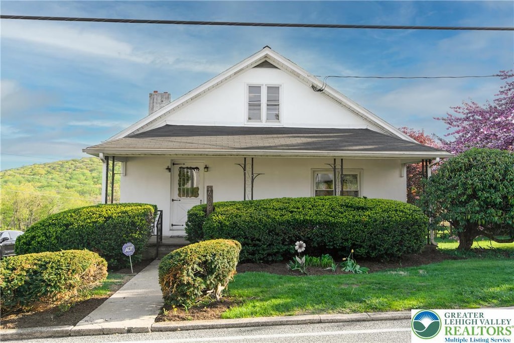 6566 Kings Hwy S, Upper Milford Twp, PA 18092 - view of front of home featuring a chimney, a front lawn, a porch, and stucco siding