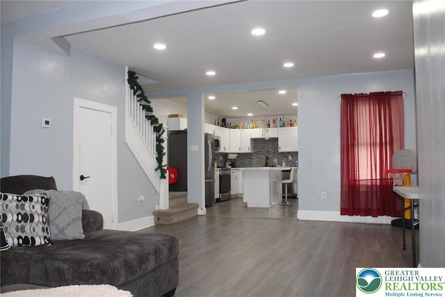 living area with recessed lighting, baseboards, stairs, and wood finished floors