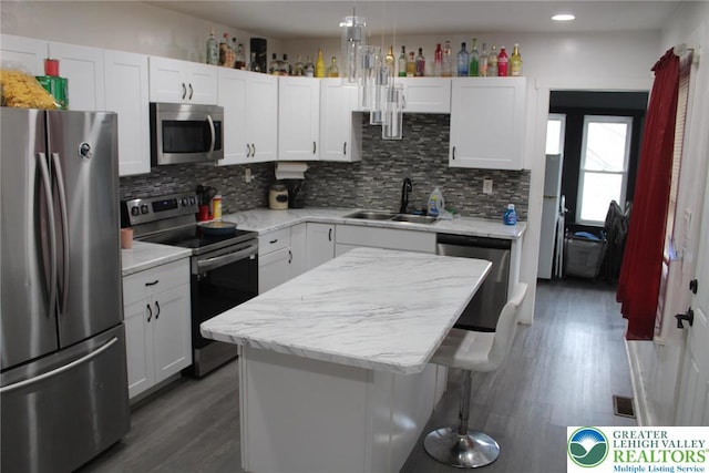 kitchen with backsplash, white cabinetry, appliances with stainless steel finishes, and a sink