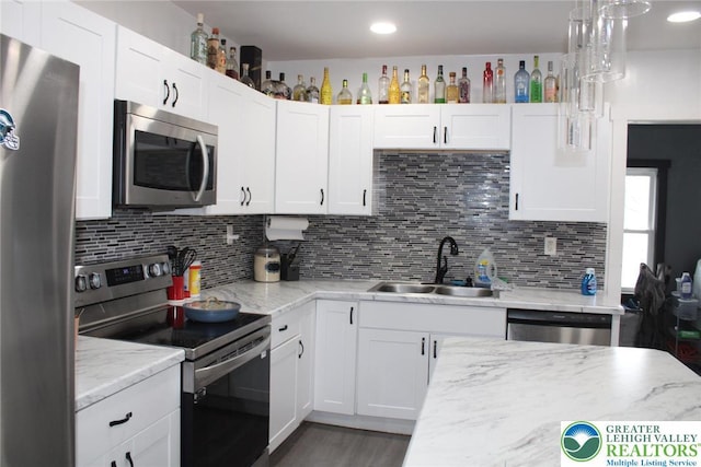 kitchen featuring a sink, white cabinetry, backsplash, and stainless steel appliances