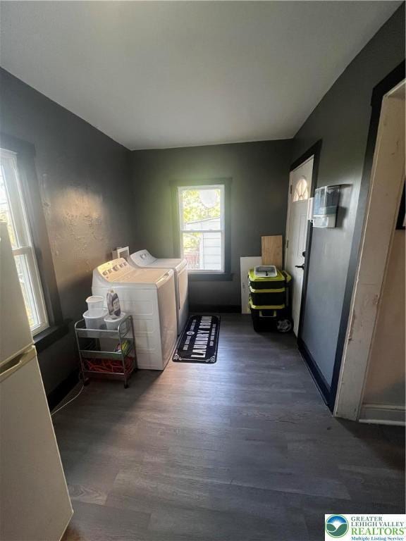 clothes washing area featuring baseboards, laundry area, washer and clothes dryer, and wood finished floors