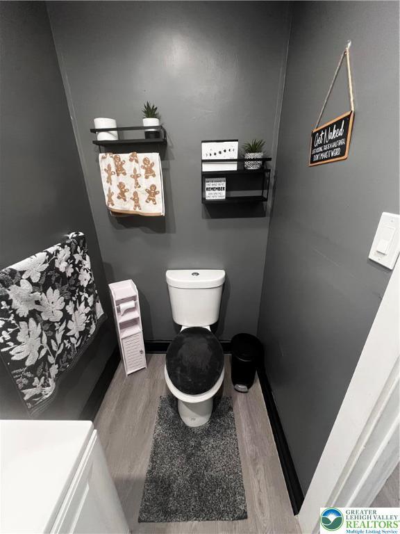 bathroom featuring toilet, baseboards, radiator heating unit, and wood finished floors