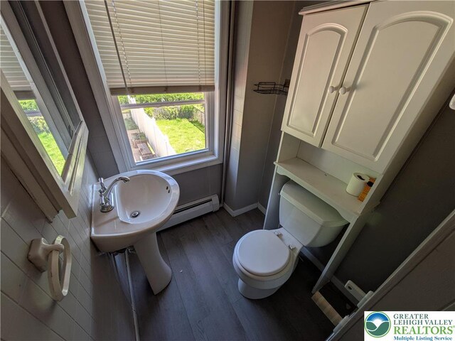half bath with toilet, baseboards, a wealth of natural light, and wood finished floors